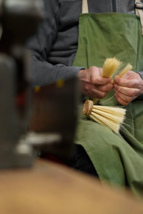 Salarié confectionnant une brosse à la main