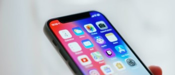 photo d'un iphone allumé tenu dans une main, on voit différentes icones d'applications sur l'écran