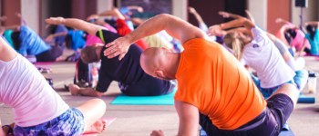 groupe de personnes en train de s'étirer le bras, assis sur des tapis de yoga