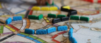 photo du plateau du jeu Les aventuriers du rails avec des pions en forme de train disposés sur une carte de chemins de fer