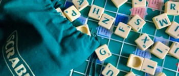 Plateau de Scrabble avec le sac des lettres renversé et des lettres renversées sur le plateau de jeu