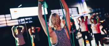 Groupe de personnes faisant du sport avec un élastique en tendant les bras vers le ciel