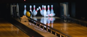 photo d'une piste de bowling avec une balle qui a touché plusieurs quilles qui sont tombées