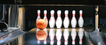 une boule de bowling glisse sur une piste vers une rangée de quilles