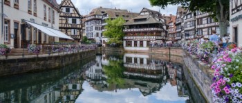 Photographie de la Petite France à Strasbourg avec l'Ill, les maisons à colombage et les quais fleuris